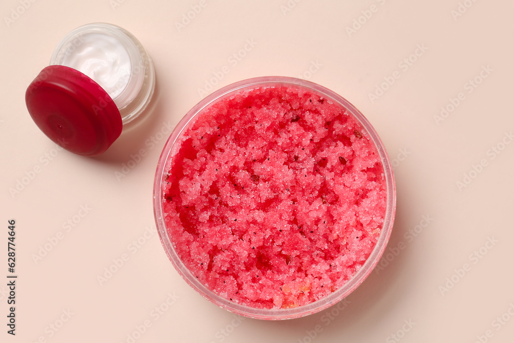 Jars with body scrub and cream on color background