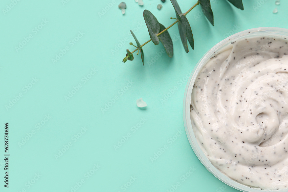 Jar of body scrub and eucalyptus branch on color background