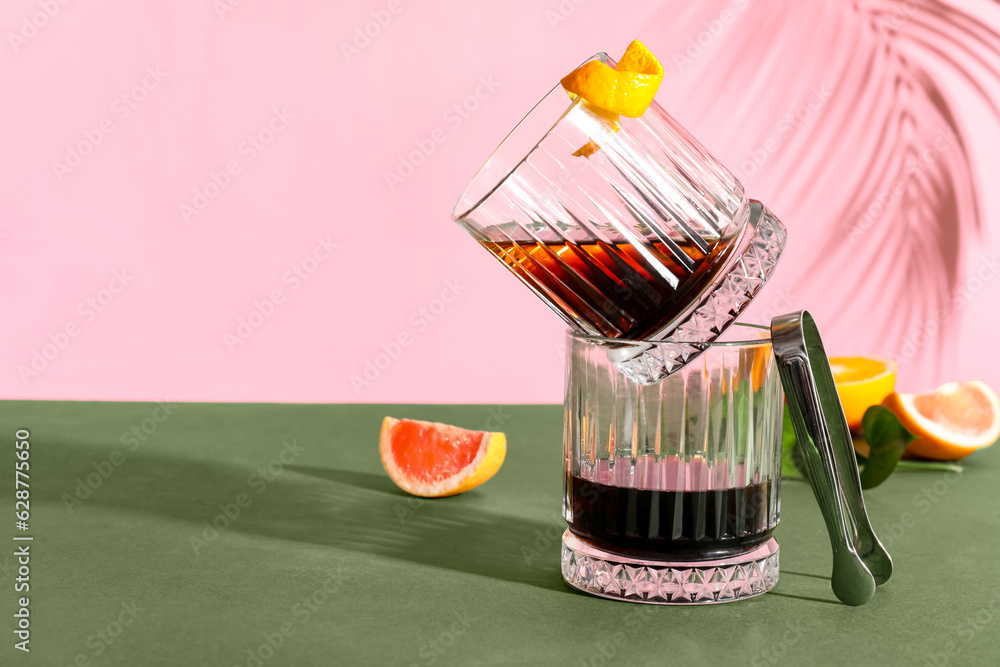 Glasses of rum, grapefruit and ice tongs on colorful background