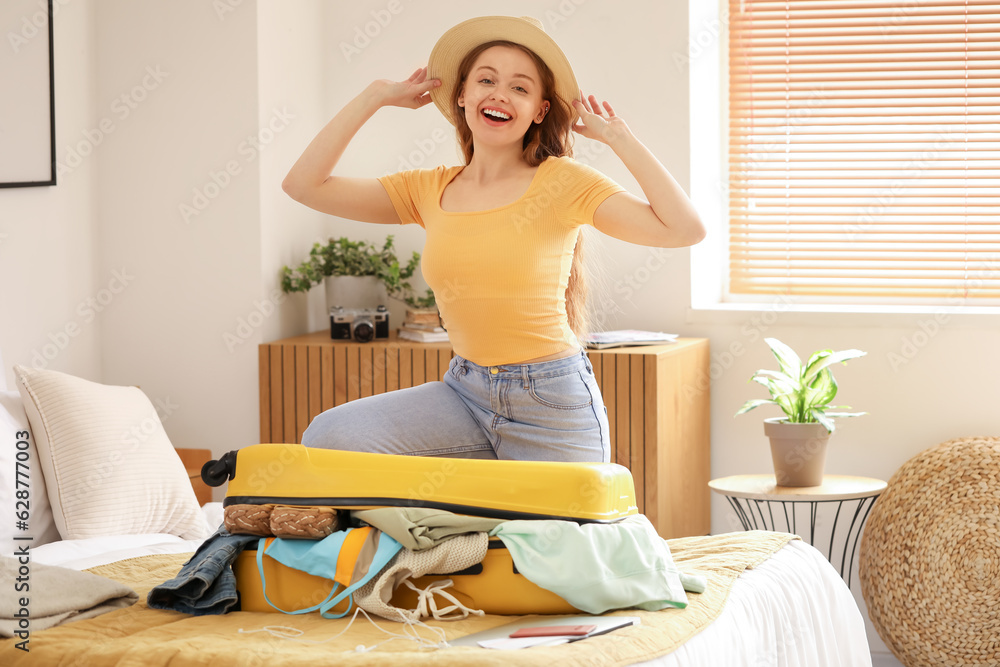 Young woman packing her clothes for travelling in bedroom