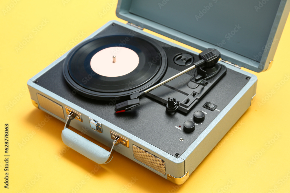 Record player with vinyl disk on yellow background, closeup