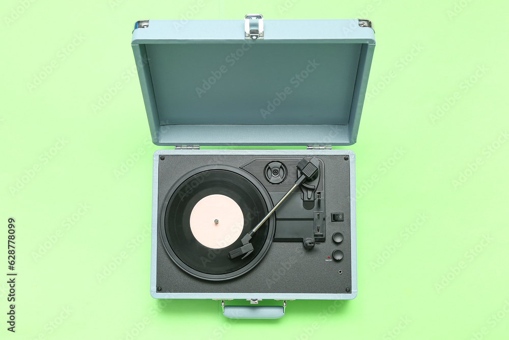 Record player with vinyl disk on green background