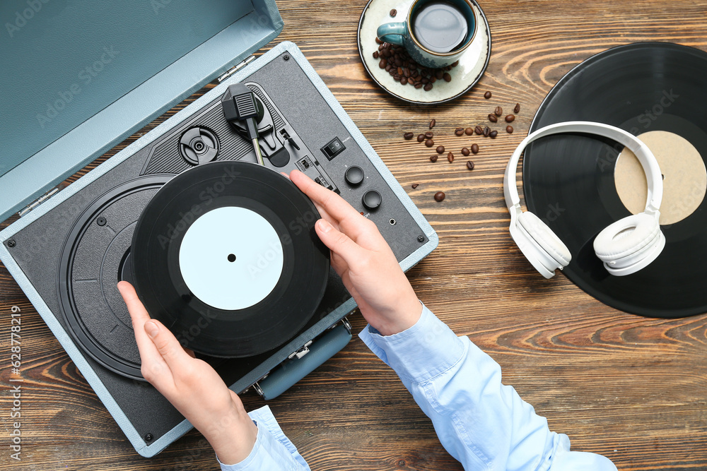 Woman with vinyl disk and record player on wooden background