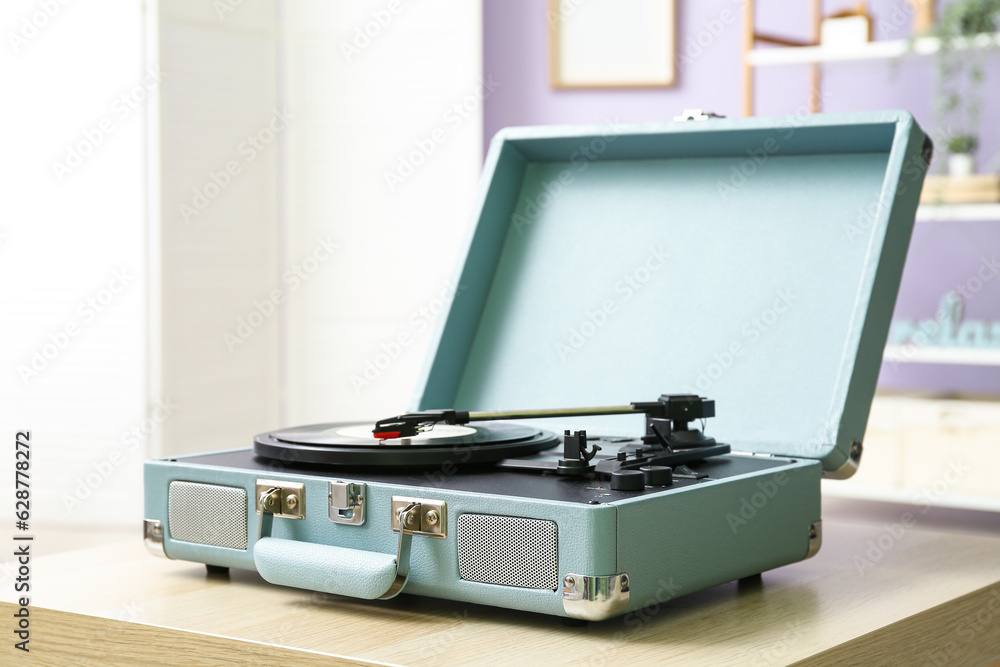 Record player with vinyl disk on table in room