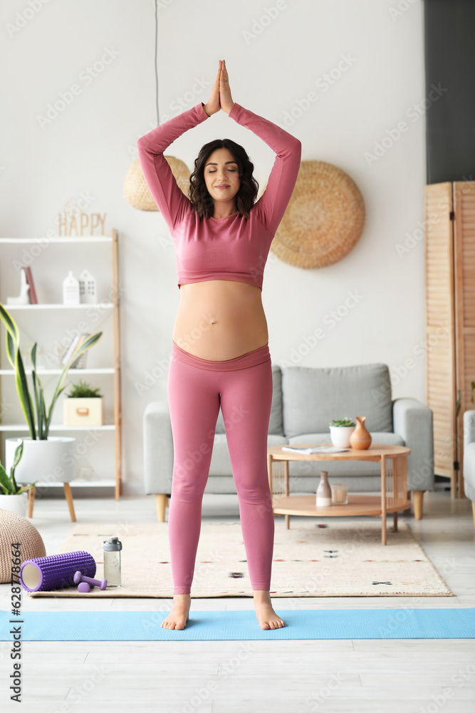 Sporty pregnant woman meditating at home