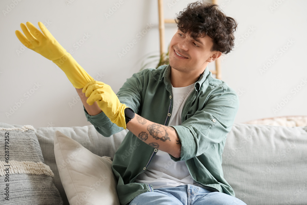 Young man putting rubber gloves at home