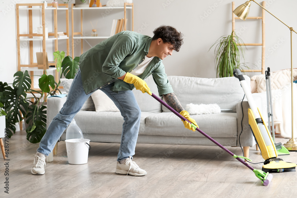 Young man mopping floor at home