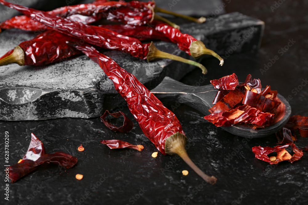 Board with dry hot chili peppers on dark background