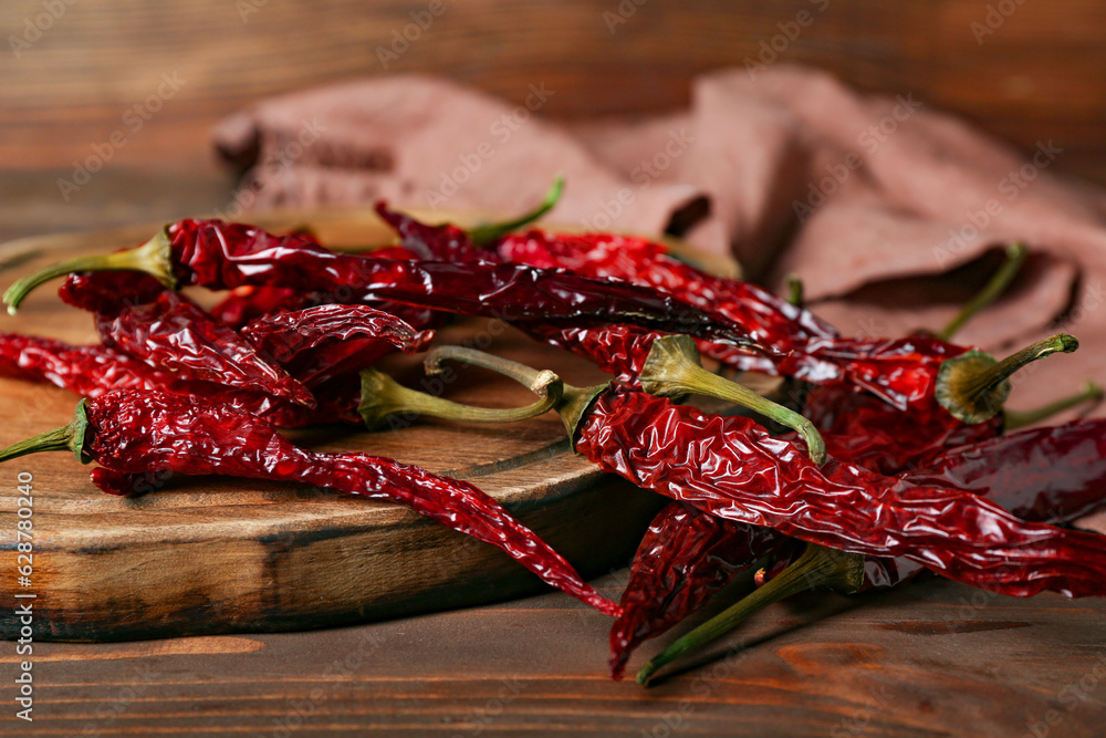 Board with dry hot chili peppers on brown wooden background