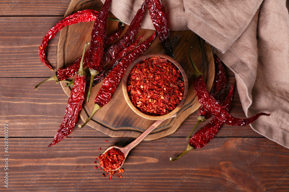 Composition with dry hot chili peppers and spice on brown wooden background