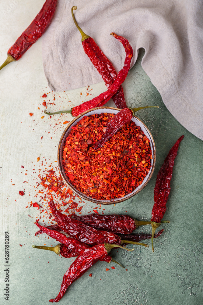 Bowl of ground peppers with dry hot chili on light background