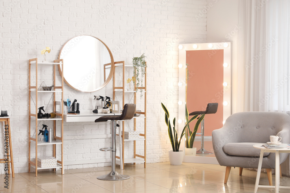 Interior of beauty salon with hairdressing table, armchair and mirrors