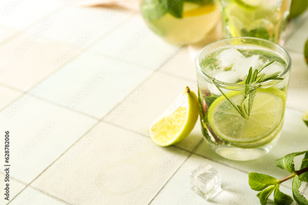 Glass of tasty mojito on light tile background