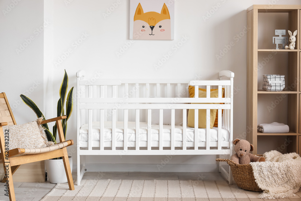 Interior of light bedroom with baby crib and shelving unit