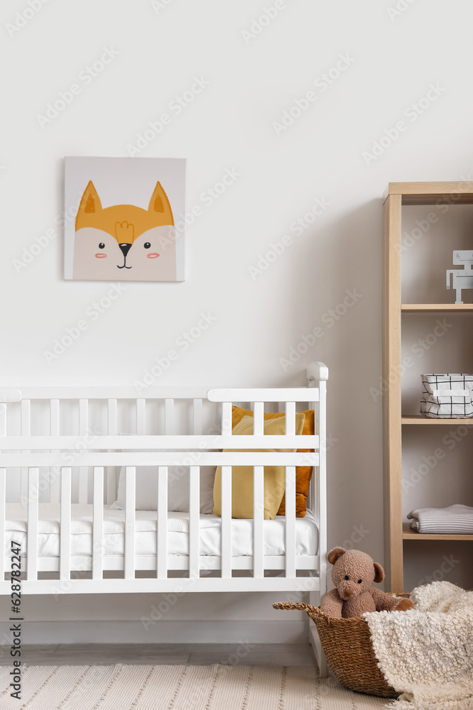 Interior of light bedroom with baby crib and shelving unit