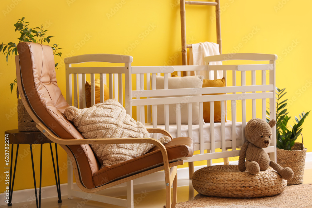 Interior of stylish bedroom with baby crib, armchair and ladder