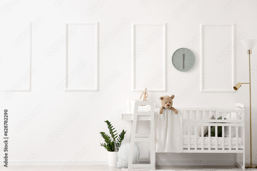 Interior of light bedroom with baby crib and changing table