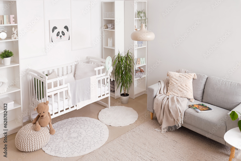 Stylish interior of childrens room in white tones with baby bed and shelving unit