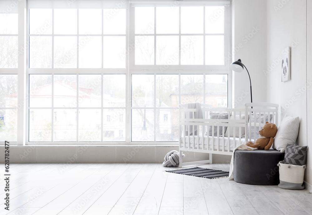 Stylish interior of childrens room  with baby bed and ottoman