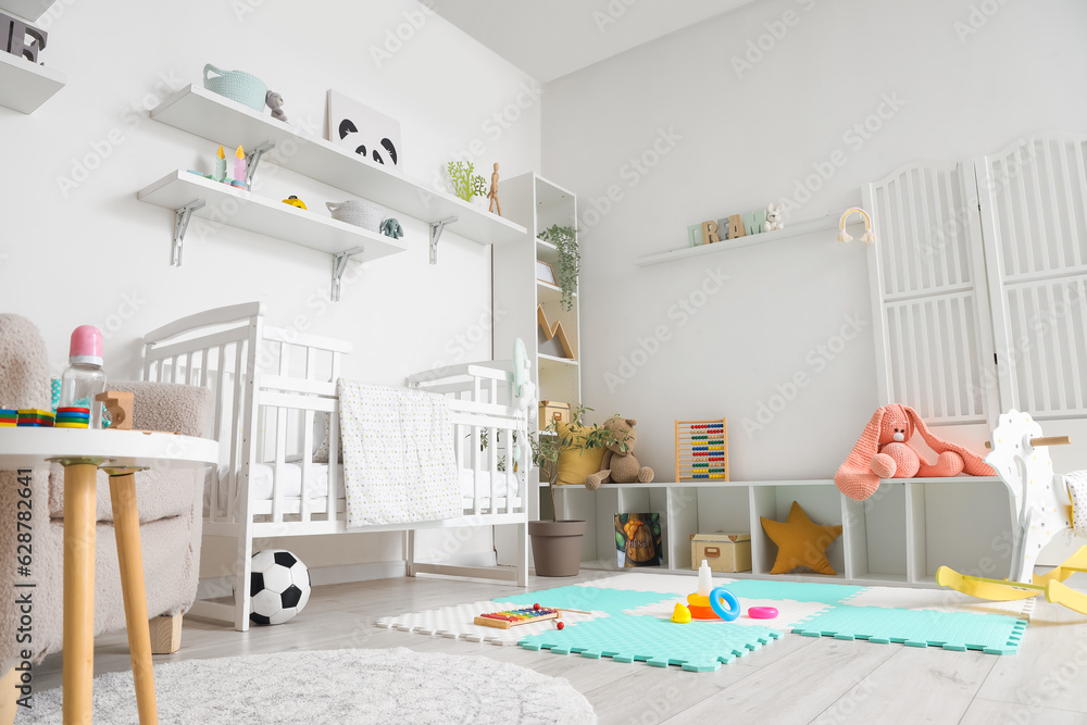 Stylish interior of childrens room with baby bed and toys