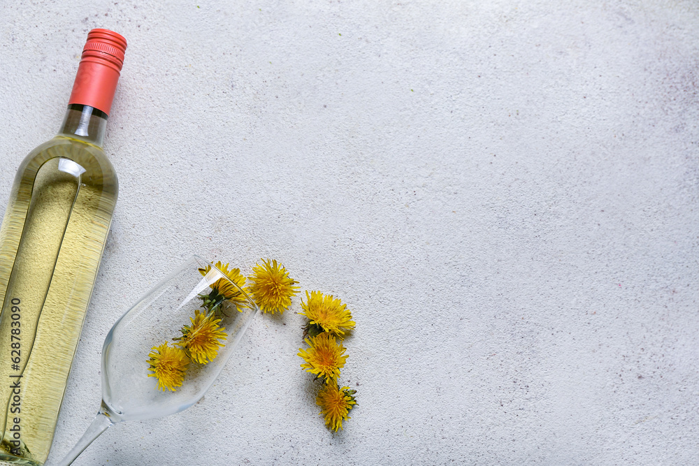 Bottle and glass of dandelion wine on white background