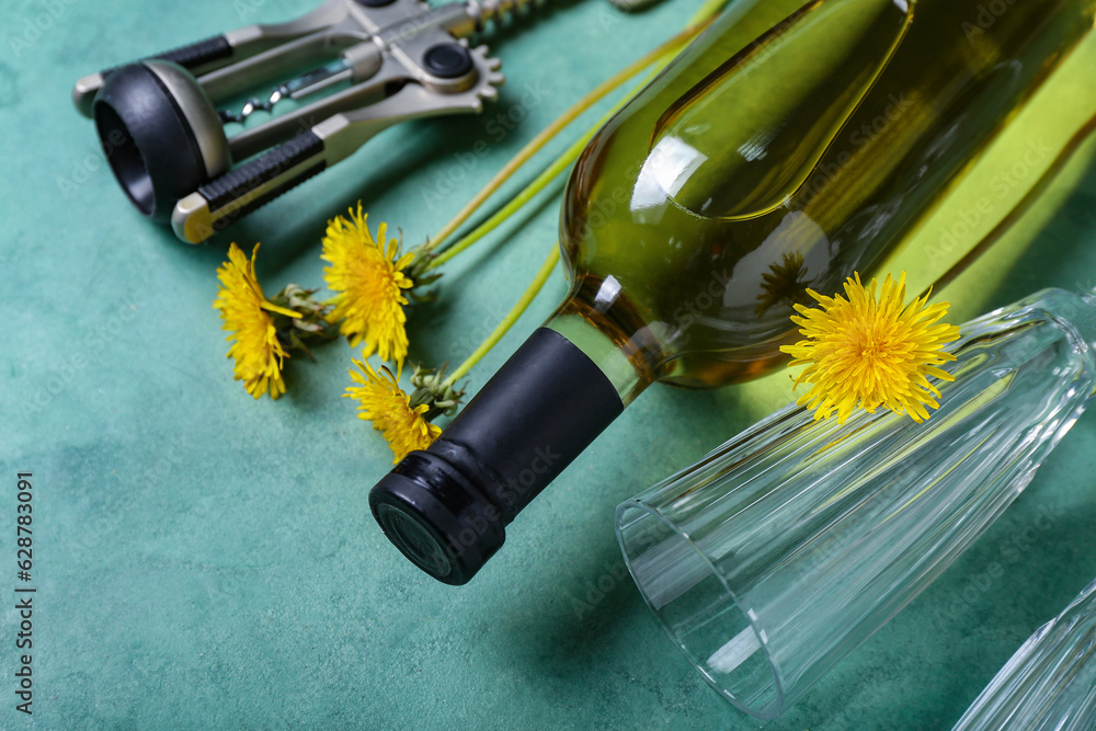 Bottle and glasses of dandelion wine on green background