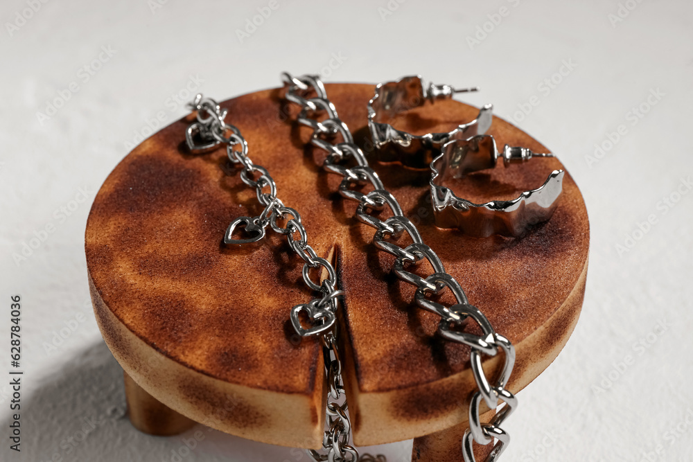 Decorative stand with silver earrings and bracelets on white textured background