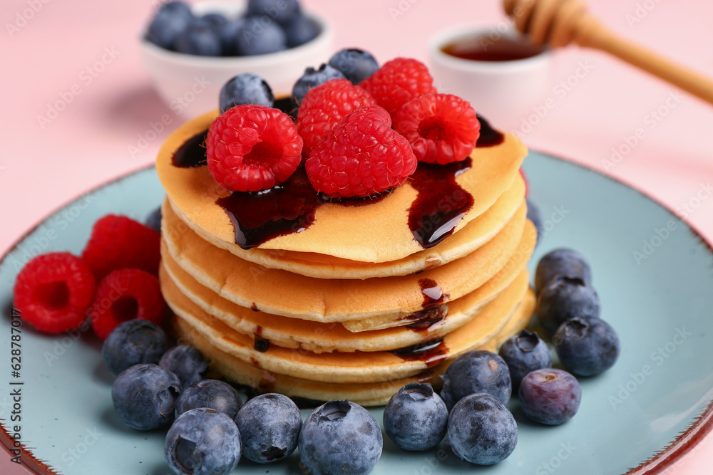 Plate with sweet pancakes and berries on pink background, closeup