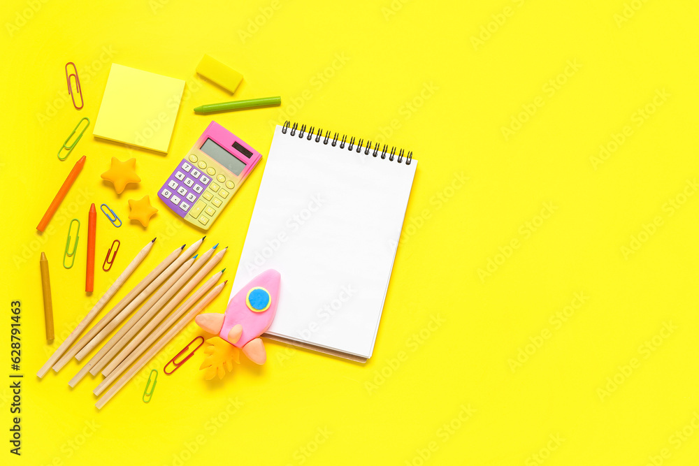 Blank notebook with rocket made of plasticine and stationery on yellow background