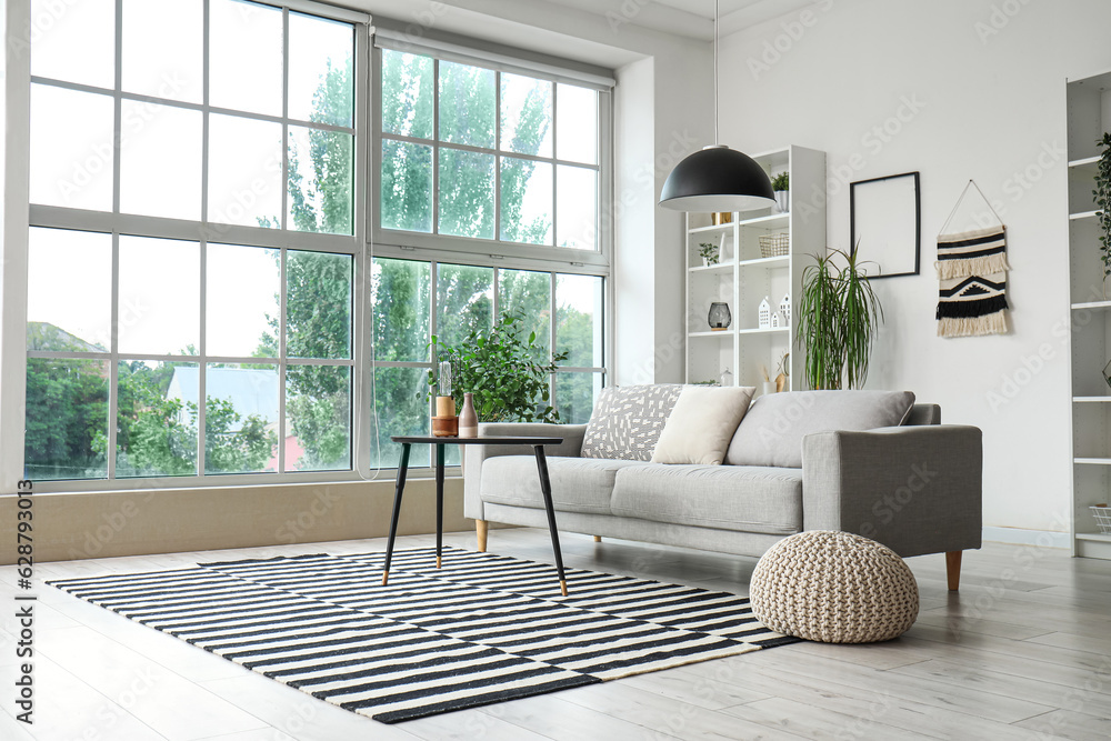 Interior of stylish living room with grey sofa, coffee table and big window