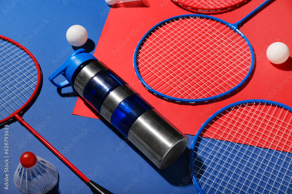 Composition with bottle of water, rackets, balls and shuttlecock on color background