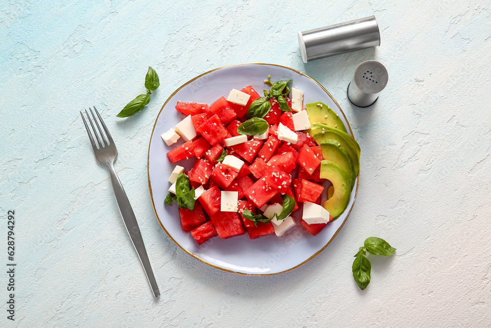 Plate of tasty watermelon salad on light blue background