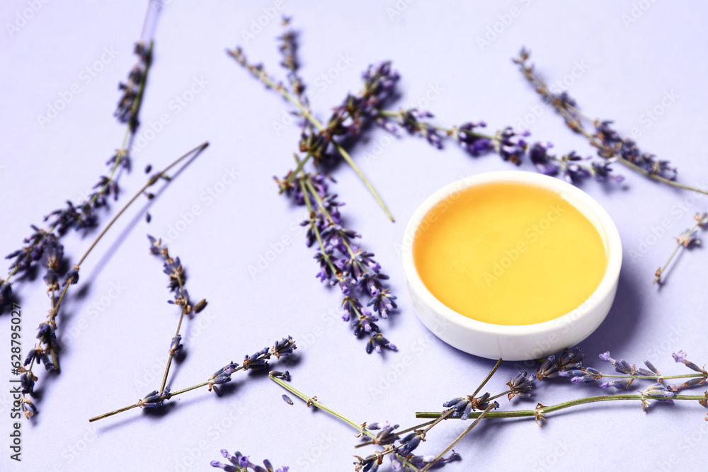 Bowl of sweet lavender honey and flowers on blue background