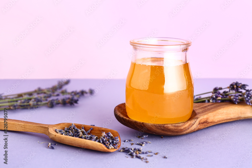 Jar of sweet lavender honey and flowers on lilac table