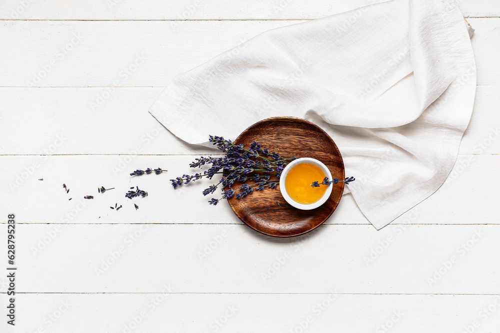 Plate with bowl of sweet lavender honey and flowers on white wooden background