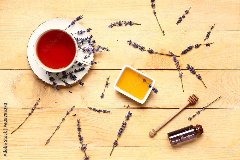 Bowl with sweet lavender honey and cup of tea on wooden background