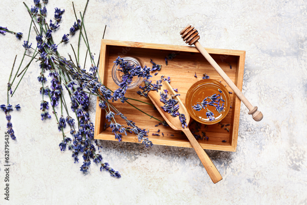 Wooden box with jar of sweet lavender honey, dipper and flowers on white background