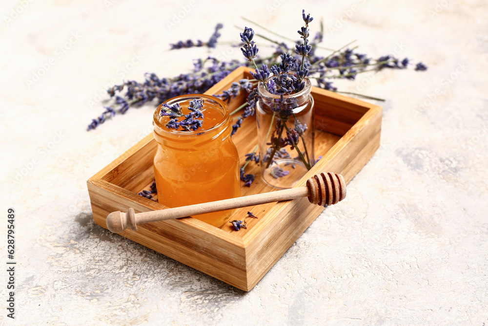 Wooden box with jar of sweet lavender honey, dipper and flowers on white background