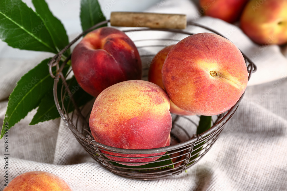 Basket with sweet peaches and leaves, closeup