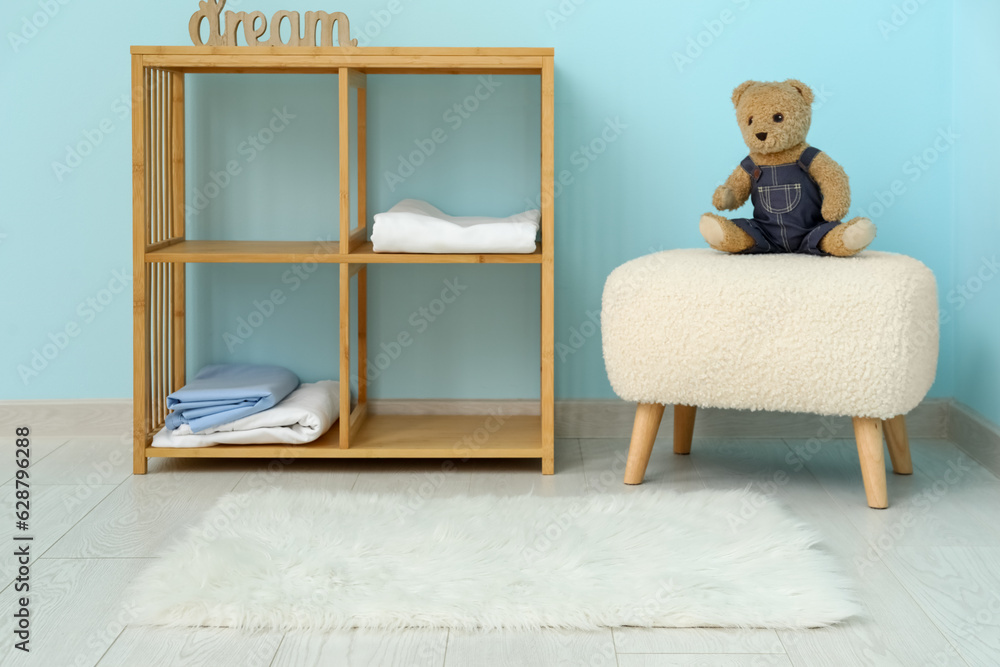 Interior of childrens room with shelving unit, teddy bear and white fur rug