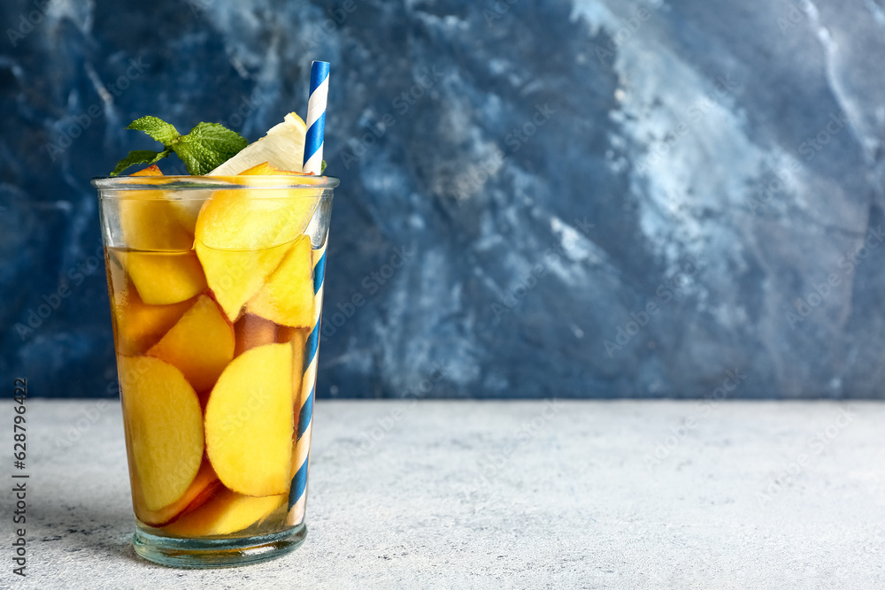 Glass of fresh peach lemonade with mint on white table