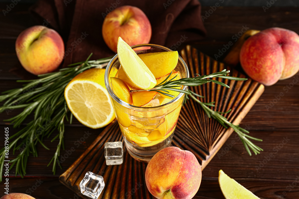 Board with glass of fresh peach lemonade and rosemary on wooden table