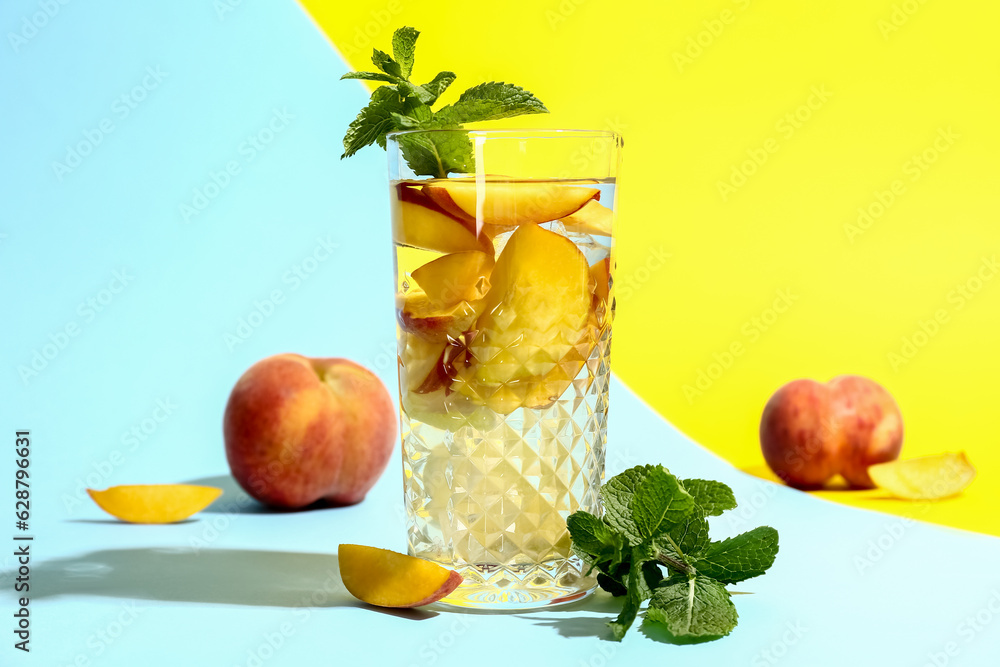 Glass of fresh peach lemonade with mint on colorful background