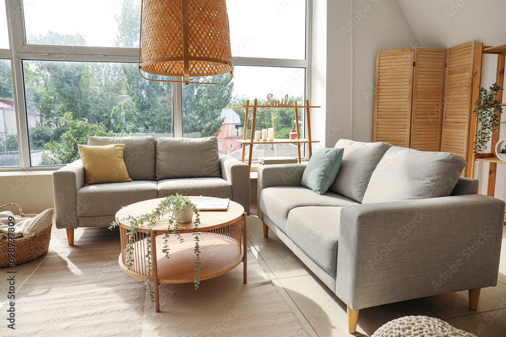 Interior of light living room with cozy grey sofas and wooden coffee table