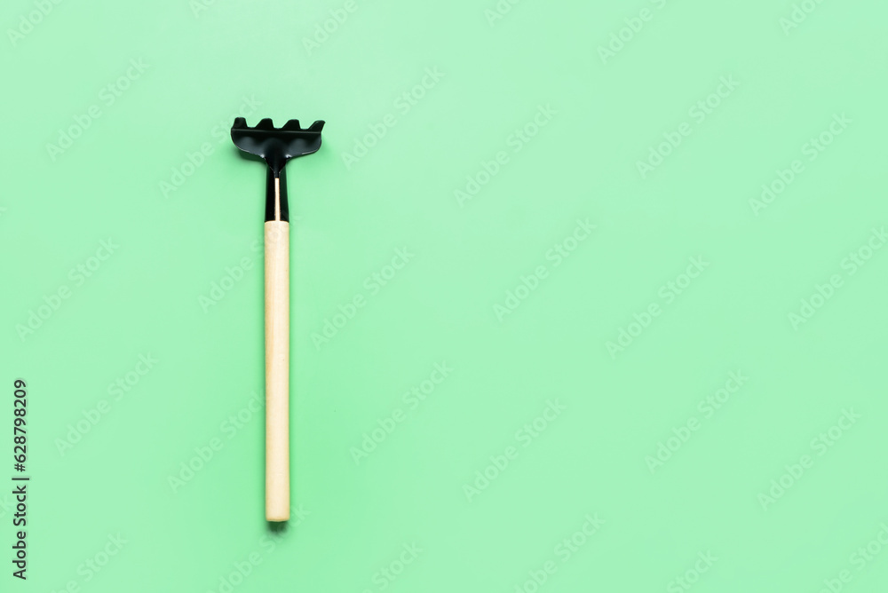 Gardening rake on green background