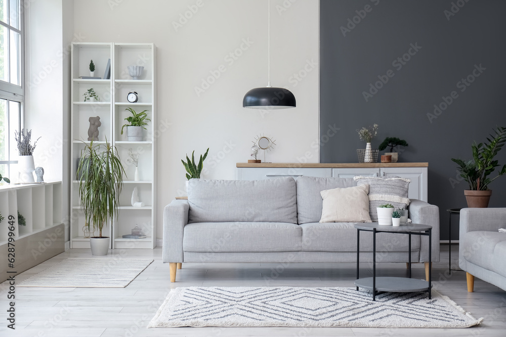 Interior of light living room with comfortable grey sofa and coffee table