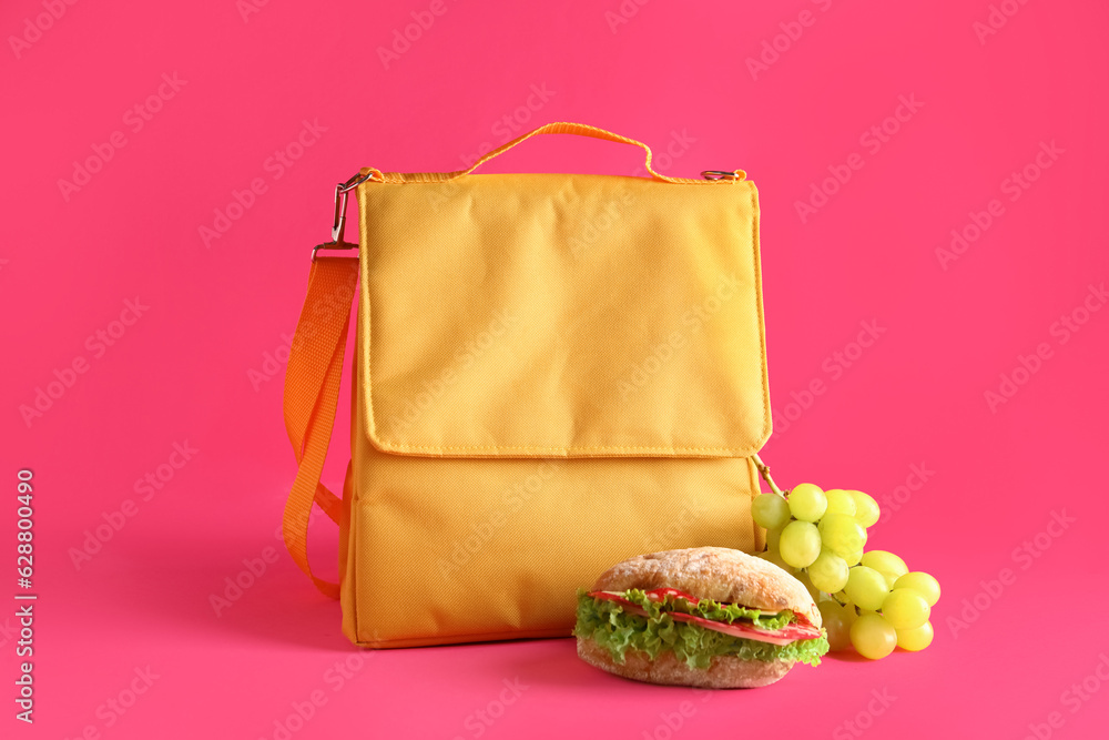 Lunch box bag with sandwich and grapes on pink background