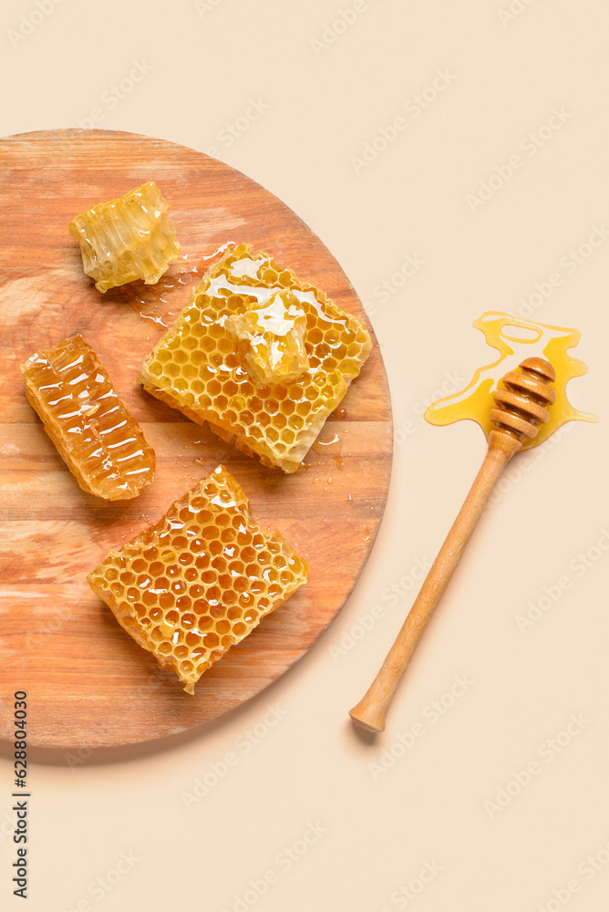 Wooden board with sweet honeycombs and dipper on yellow background