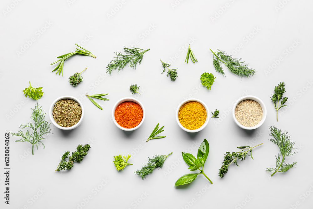 Composition with bowls of spices and fresh herbs on light background