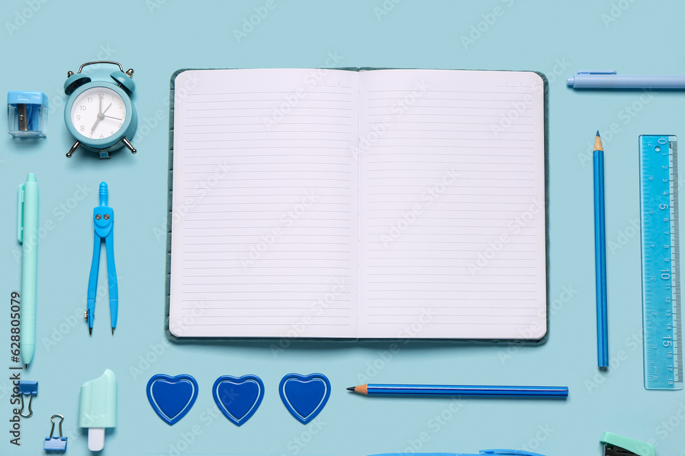 Notebook with different stationery supplies on blue background